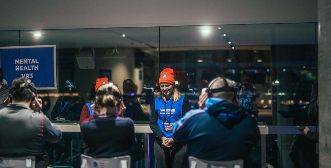 A photo of several young people wearing beanies and virtual reality glasses in a room. 2 of them are wearing Vinnies vests over their clothes.