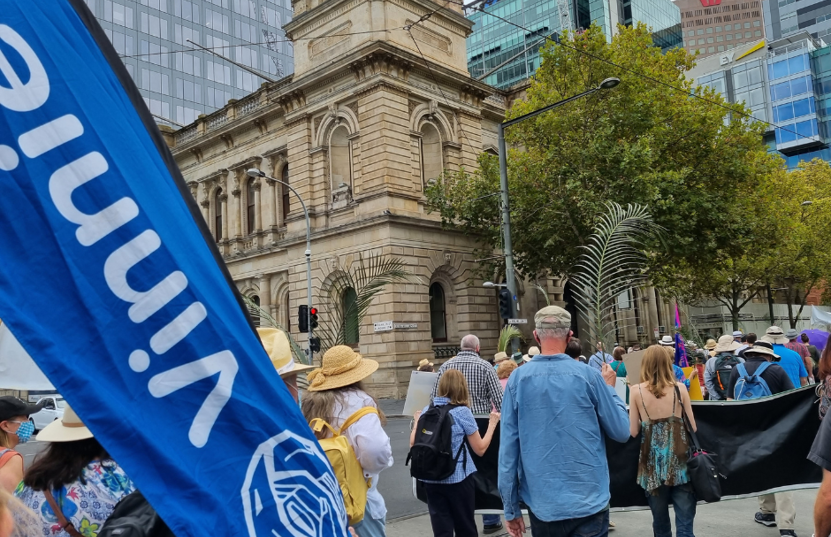 A photo of people marching at a rally, including a Vinnies banner on Palm Sunday.