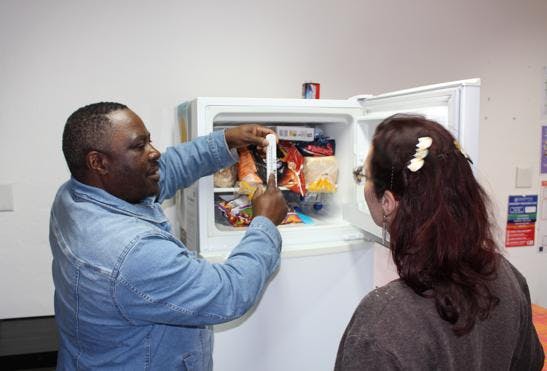 A man showing the temperature of the freezer, explaining how to be energy efficient.