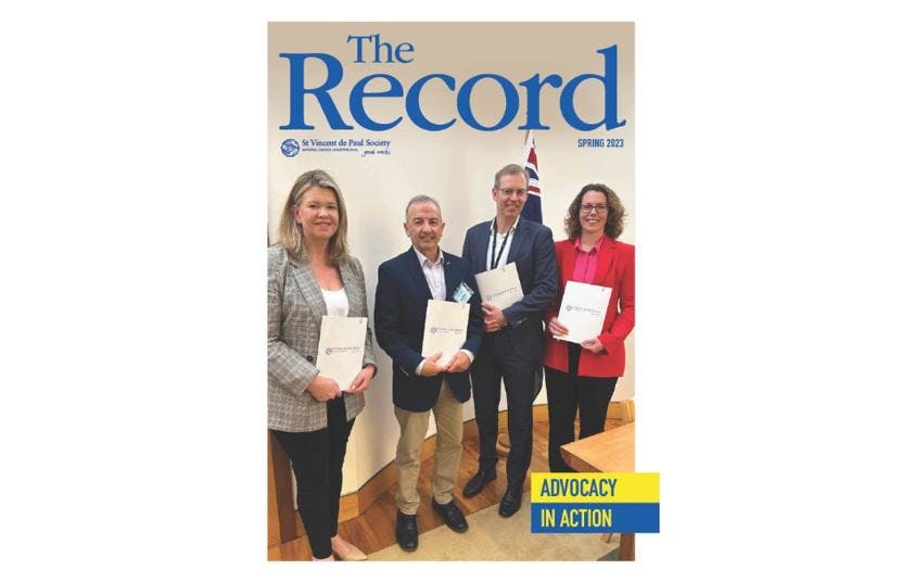 Cover of The Record showing title and edition info and a picture of 4 people holding a report and facing the camera.