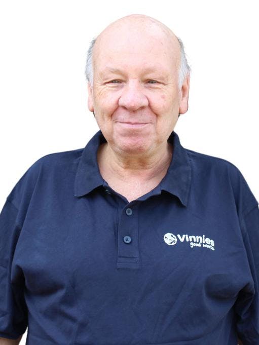 A smiling man wearing a dark blue Vinnies t-shirt