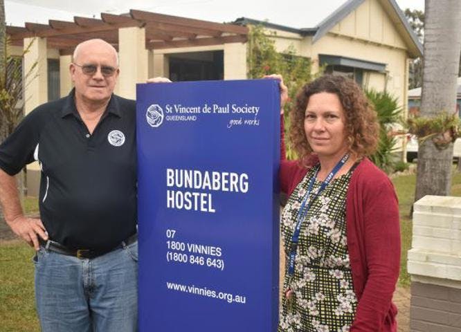 Bundaberg Hostel sign with Members/Staff standing beside it