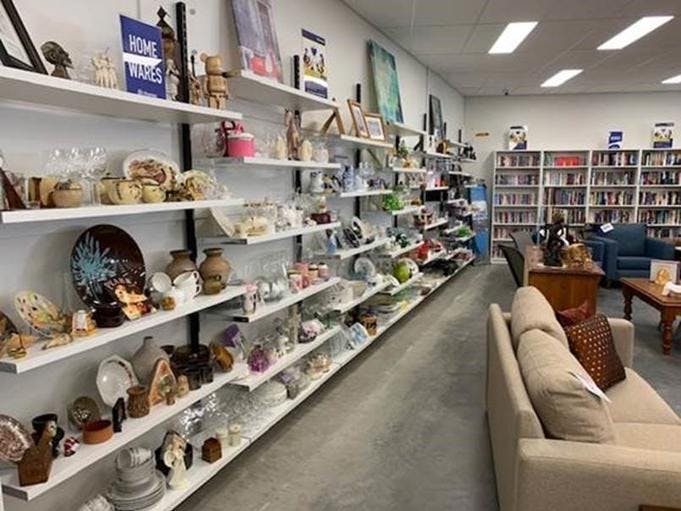 A photo of the inside of Vinnies Shop Australind, showing shelves containing second hand shoes along a white wall.