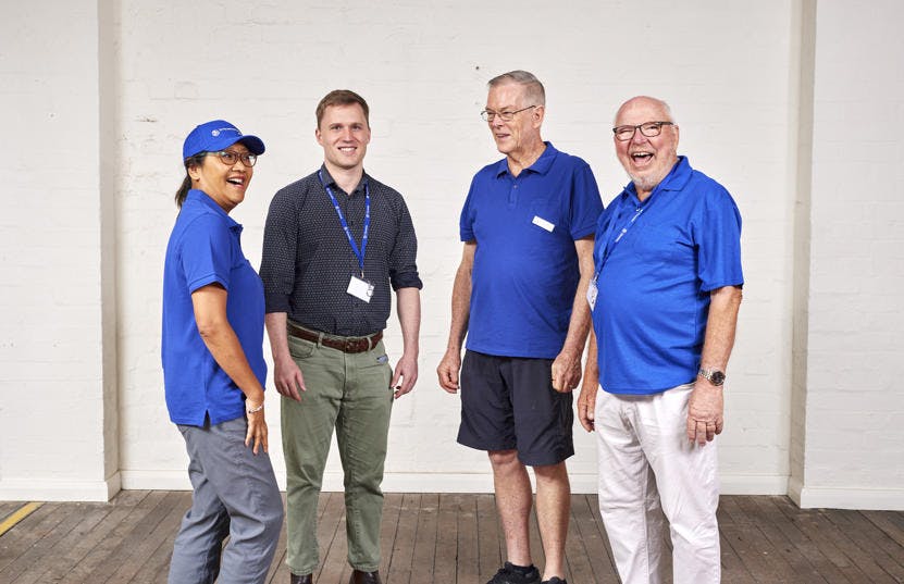 A photo of a group of Vinnies WA volunteers facing the camera. 3 of them are wearing blue jersey pique and the last one is wearing a lanyard. They are all smiling.