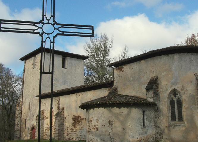 A photo of an old church in France with a metal cross in the foreground.