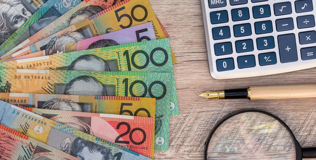 Australian Currency on table with calculator and magnifying glass