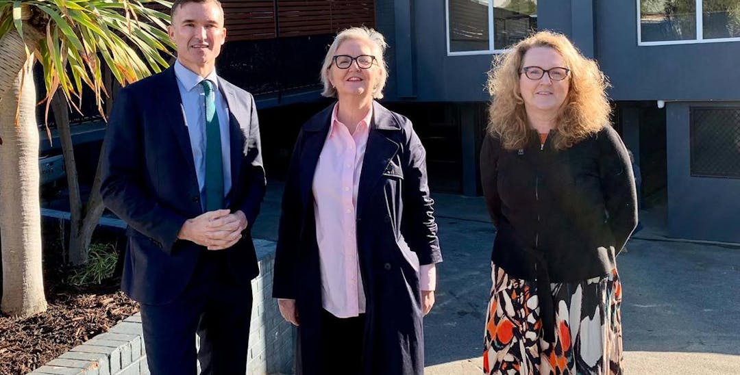 A photo of Vinnies acting CEO Ann Curran, Housing Minister John Carey and Nedlands member Dr Katrina Stratton, looking at the camera standing in the sun. The photo is taken outside a black apartment complex.