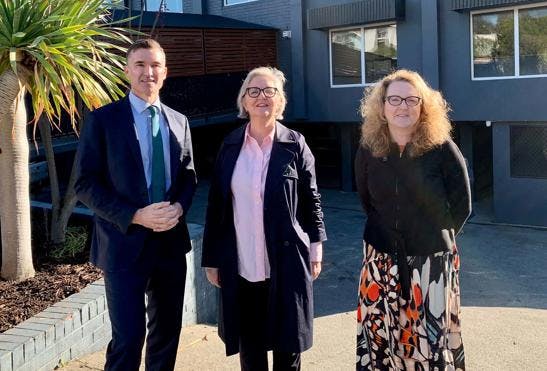 A photo of Vinnies acting CEO Ann Curran, Housing Minister John Carey and Nedlands member Dr Katrina Stratton, looking at the camera standing in the sun. The photo is taken outside a black apartment complex.