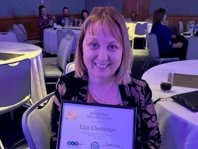 A photo of Vinnies financial counsellor Liza Chatterton smiling to the camera, holding a framed award for Established Practice