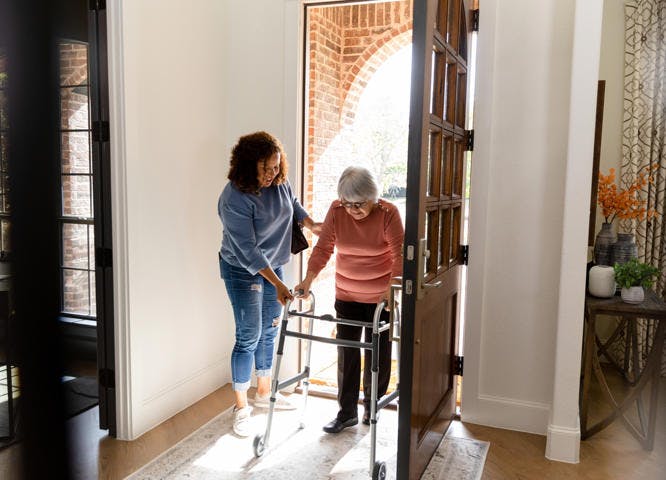 Vinnies volunteer helping elderly companion into their house