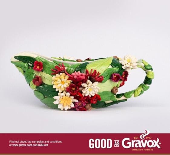 A white gravy boat that has been decorated with colourful flowers.