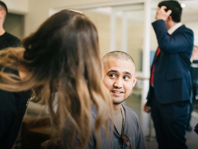 A photo of a young man looking at his female hairdresser and smiling