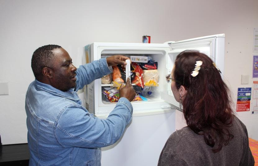 A man showing the temperature of the freezer, explaining how to be energy efficient.