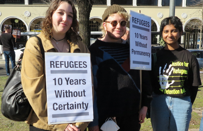 3 young people with banners saying Refugees - 10 years without certainty